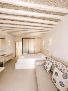 a bedroom with two beds and a couch at Cozy apartments Paros Kostos in Kóstos