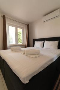 a large bed with two white pillows and a window at Starfish Apartments in Sutivan