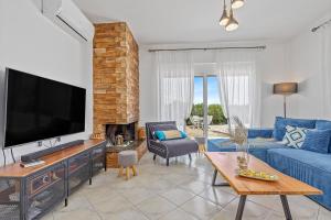 a living room with a blue couch and a tv at S-EVA RESORT in Kolymbia