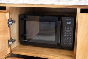 a black microwave in a wooden kitchen cabinet at Aqueduct resort in Ko Tao