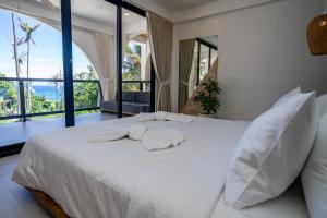 a white bed in a room with large windows at Aqueduct resort in Ko Tao