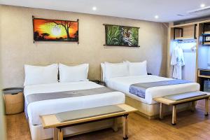 a hotel room with two beds and paintings on the wall at La Maison Royale South C in Nairobi