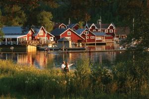 two people in a boat in a river with houses at Norrfällsvikens Vandrarhem in Mjällom