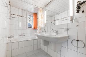 a white bathroom with a sink and a bath tub at Atlantis Apartments by MEIN SAMNAUN - MOUNTAIN HOMES in Samnaun +52 photos