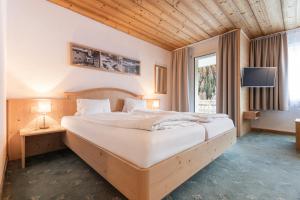 a bedroom with a large white bed with a television at Atlantis Apartments by MEIN SAMNAUN - MOUNTAIN HOMES in Samnaun