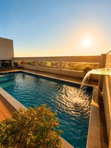 a swimming pool with a fountain on a building at Hotel Arujá in Arujá