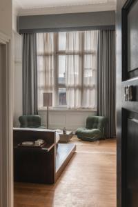 a living room with two green chairs and a window at Arthouse Glasgow - Newly Refurbished in Glasgow