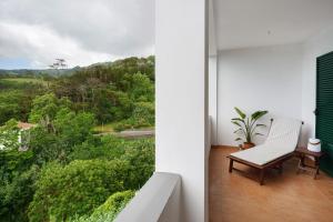 a balcony with a white chair and a view of trees at Beach House - Mountain And Ocean in Porto Formoso