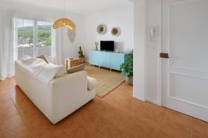a living room with a white couch and a television at Beach House - Mountain And Ocean in Porto Formoso