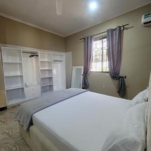 a bedroom with a large white bed and a window at Mary homestays in Dar es Salaam