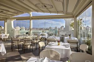 a restaurant with tables and chairs and large windows at NH Collection Madrid Gran Vía in Madrid