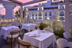 a restaurant with white tables and chairs and a building at NH Collection Madrid Gran Vía in Madrid +56 photos