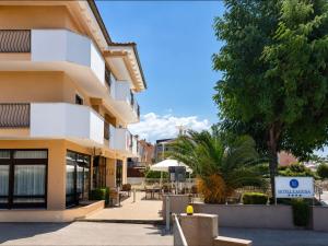a building with a palm tree next to a street at Hotel Laguna in Privlaka