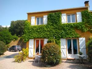 a house covered in ivy with a table and chairs at Chez Nat et JC in Eccica-Suarella