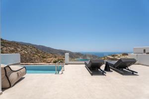 a patio with two lounge chairs next to a pool at Serenity Villas in Ios Chora