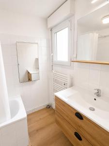 a white bathroom with a sink and a mirror at Appartements à Oloron in Oloron-Sainte-Marie +9 photos