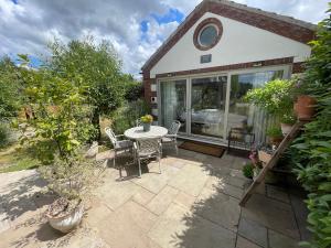 a patio with a table and chairs in a yard at Lavender Lodge in Briston