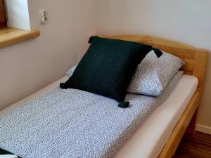 a bed with a black pillow on top of it at Zielony Zakontek in Ratułów +2 photos