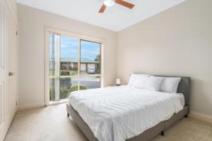 a white bedroom with a bed and a large window at Leopold holiday home in Leopold