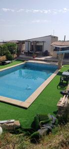 a swimming pool with green grass and a house at Villa Oliva Torotto in Niscemi