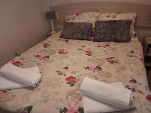 a bed with a floral bedspread and pillows on it at Mobillehome Camp Turanj in Turanj