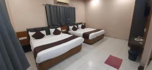 two beds in a hotel room withskirts at Hotel Purushottam in Dwarka