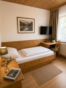 a bedroom with a bed and a desk with a television at Hotel Hello in Monguelfo
