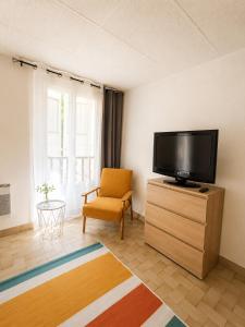 a living room with a flat screen tv and a chair at Studio spacieux centre-ville avec ascenseur - Le Bohème in Digne-les-Bains