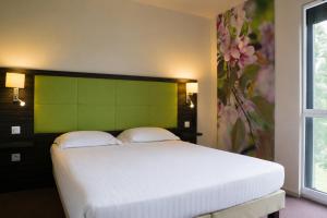 a bedroom with a large white bed with a green headboard at The Originals City, Hôtel La Verriaire, Cholet Sud in La Verrie
