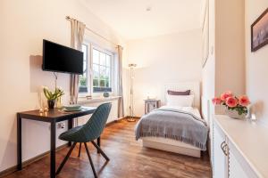 a bedroom with a bed and a desk and a television at Gästehaus Daheim in Scharbeutz