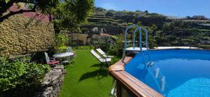 a swimming pool in a yard with a table and a bench at Quinta do Ribeiro Real in Câmara de Lobos