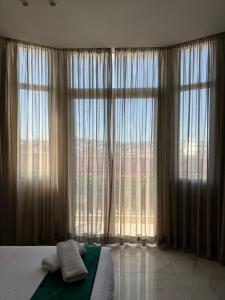 a bedroom with a bed and a large window at Hôtel Majestic Rabat Centre in Rabat