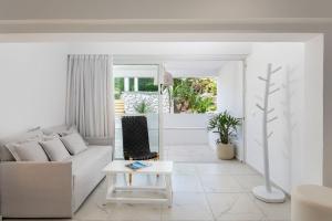 a white living room with a couch and a table at Dimitra Beach Hotel & Suites in Ágios Fokás