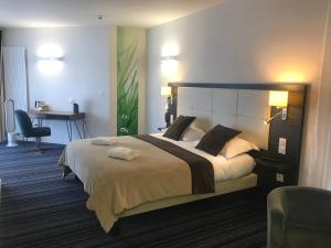 a bedroom with a large bed and a desk at The Originals City, Hôtel La Verriaire, Cholet Sud in La Verrie