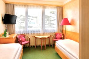 a hotel room with two beds and a table and chairs at Hotel Schrofenstein in Landeck