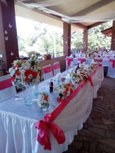 a long table with white tables with red and white flowers at Perperеshka River Villas in Stremtsi