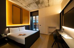 a bedroom with a bed and a desk with a book at Breda Suites Hotel Milano in Milan