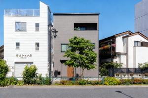 a white building with a tree next to a street at First Choice in Tokyo
