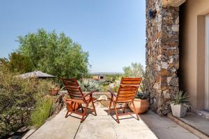 two chairs sitting on a patio with a stone wall at Casa Laderas de Chacras de Coria in Chacras de Coria +101 photos