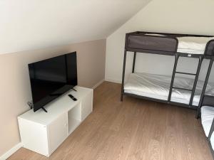 a room with two bunk beds and a flat screen tv at De Boomgaard in Nieuwerkerken