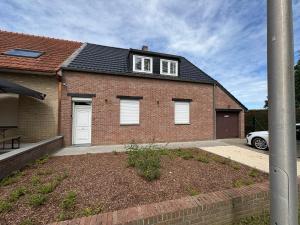 a brick house with white windows and a driveway at De Boomgaard in Nieuwerkerken