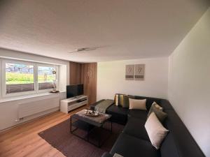 a living room with a black couch and a window at Apartment Enzian in Saas-Grund