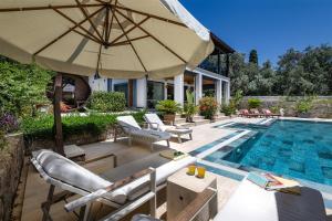 a pool with chairs and an umbrella next to a house at Sea View Villa in most upscale Yalikavak in Bodrum City