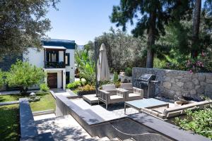 a patio with a table and an umbrella and a grill at Sea View Villa in most upscale Yalikavak in Bodrum City