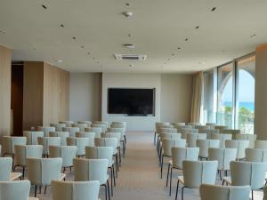 a conference room with white chairs and a flat screen tv at Green Coast Hotel MGallery Collection in Vlorë +122 photos