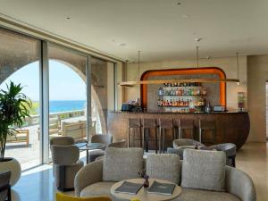 a restaurant with a bar with a view of the ocean at Green Coast Hotel MGallery Collection in Vlorë