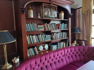 a living room with a pink couch in front of a book shelf at Víghajós Panzió in Budapest