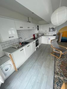 a kitchen with white cabinets and a sink and a chair at 1 Marine House in Penzance