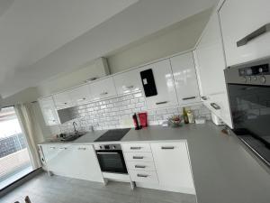 a white kitchen with white cabinets and a stove at 1 Marine House in Penzance +3 photos