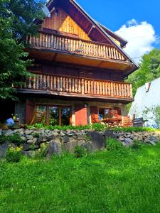 a large log cabin with a porch and a yard at Leśny Poranek in Iwkowa